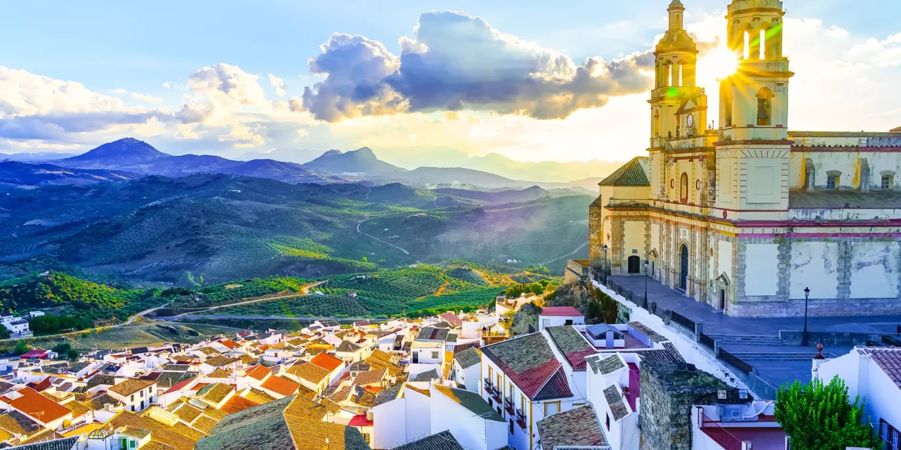 Blick von oben auf eine Kirche in Cádiz in Andalusien, umgeben von weißen Häusern und grüner Landschaft.
