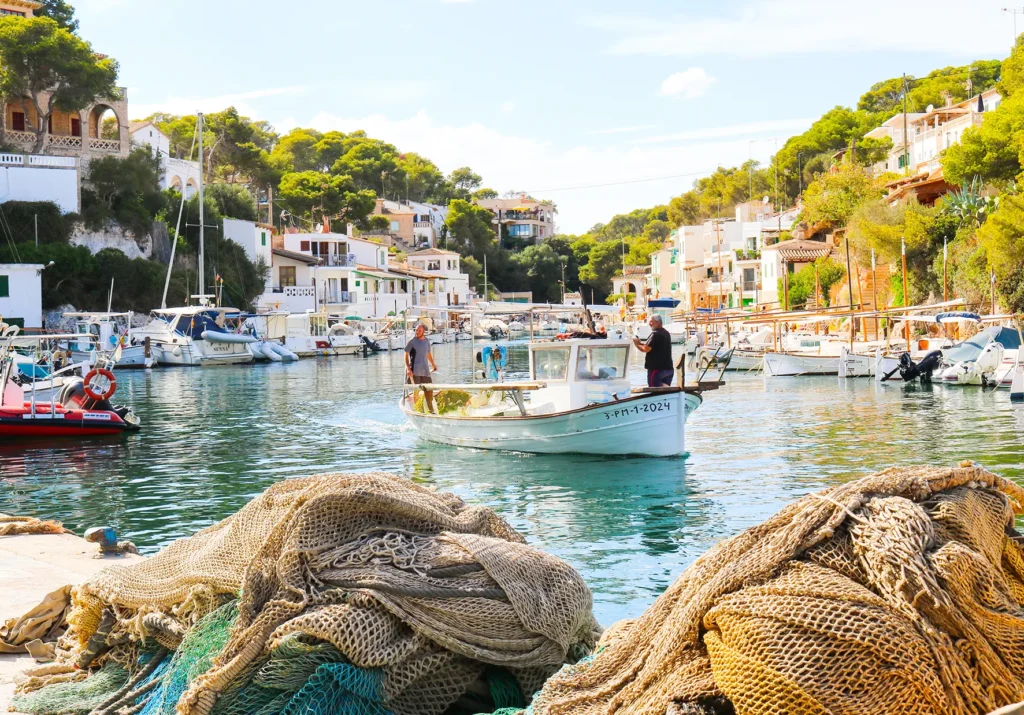 Der Hafen von Cala Figuera auf Mallorca mit Booten im Wasser zwischen Felsen und Häusern.