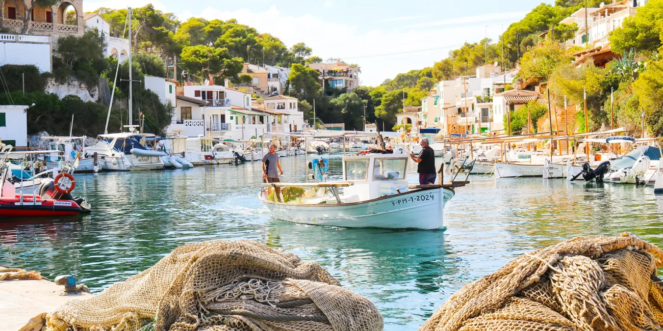 Der Hafen von Cala Figuera auf Mallorca mit Booten im Wasser zwischen Felsen und Häusern.