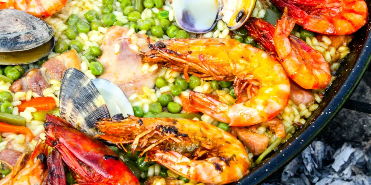 Eine typische spanische Paella wird in einer großen Pfanne mit Reis und verschiedenen Zutaten serviert.