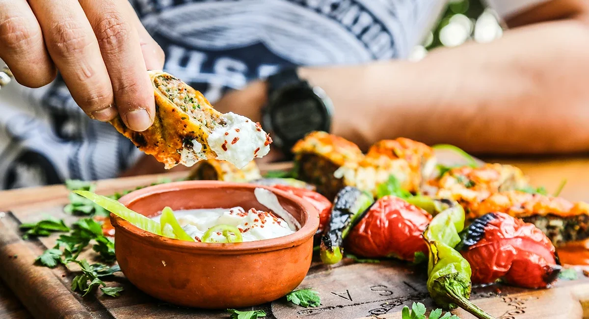 Ein Mann isst eine traditionell albanische Mahlzeit mit gegrilltem Gemüse und Joghurt-Dip.