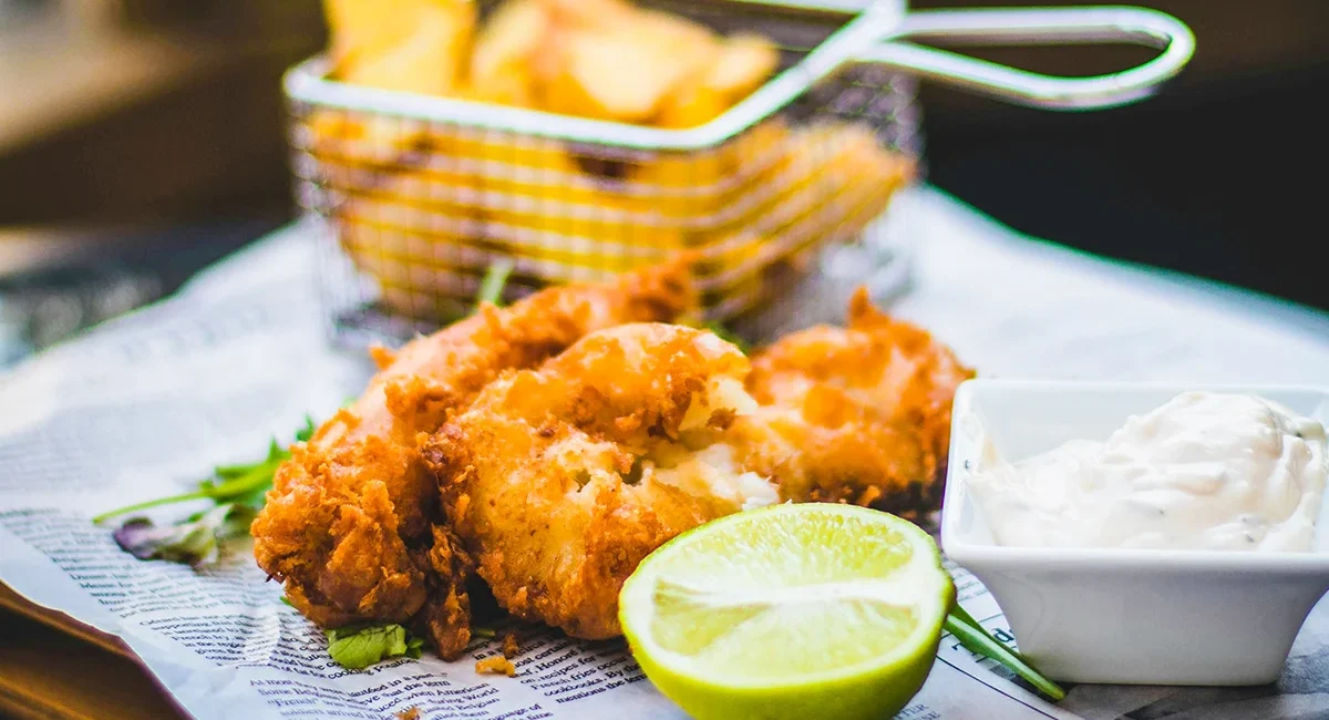 Frittierter Fisch mit Pommes, Mayonnaise und einer Limette ist eines der typischen Gerichte in Großbritannien