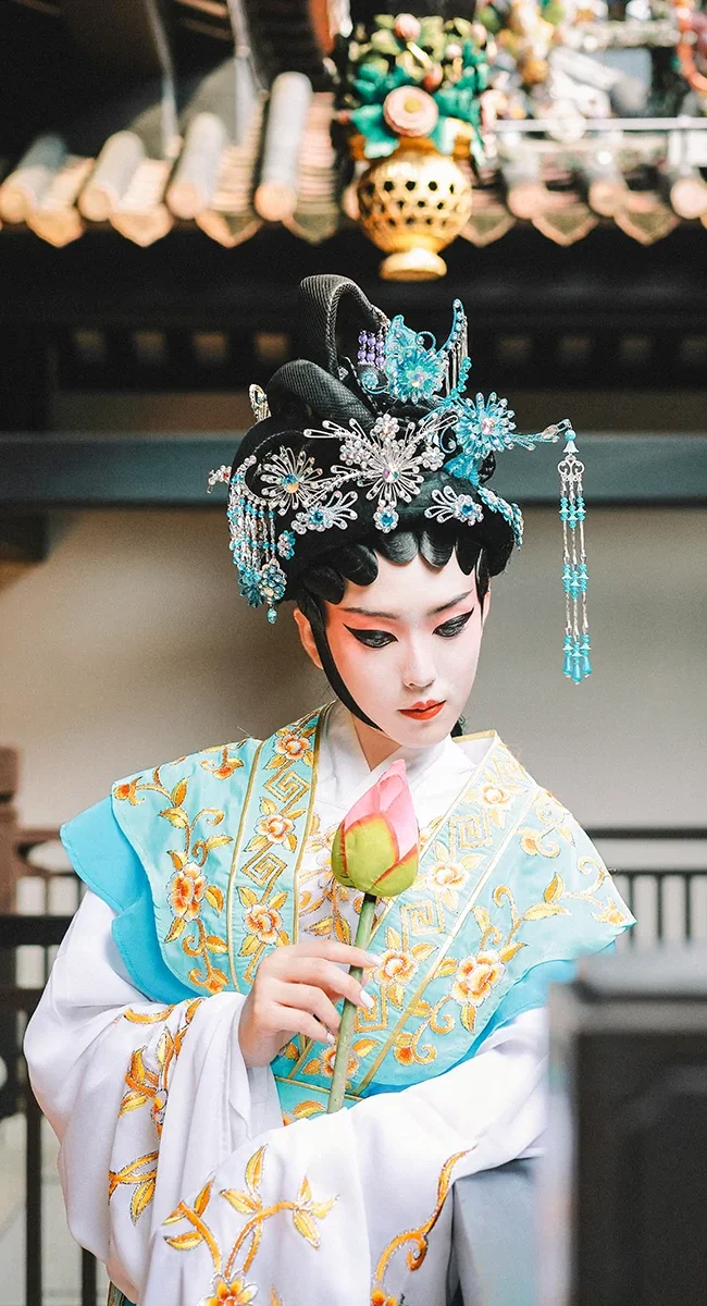 Chinesische Frau in einem traditionellen Gewand und geschmückter Maske