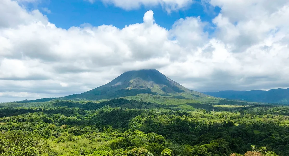 Blick auf den Vulkan Arenal in Costa Rica, der sich über die grüne Landschaft erhebt.