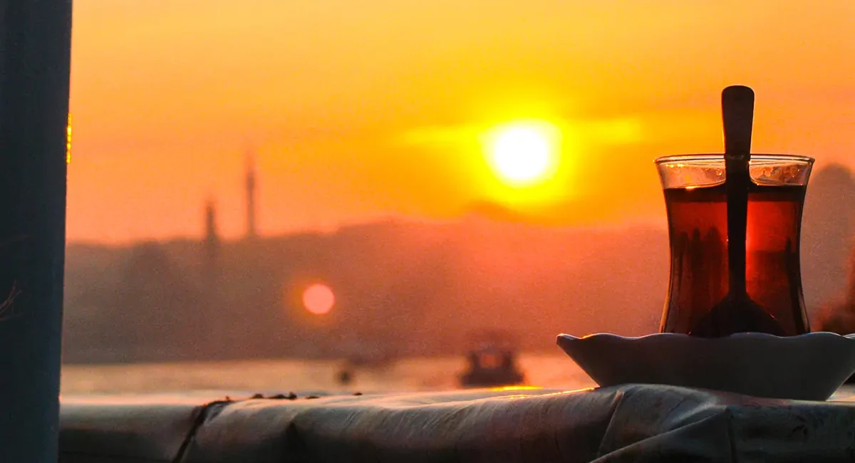 Ein türkisches Teeglas steht im warmen Licht des Sonnenuntergangs über Istanbul.