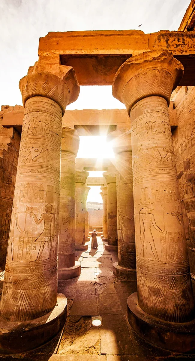 Die Sonne scheint durch die mit ägyptischen Symbolen verzierten Säulen des Karnak Tempels in Luxor