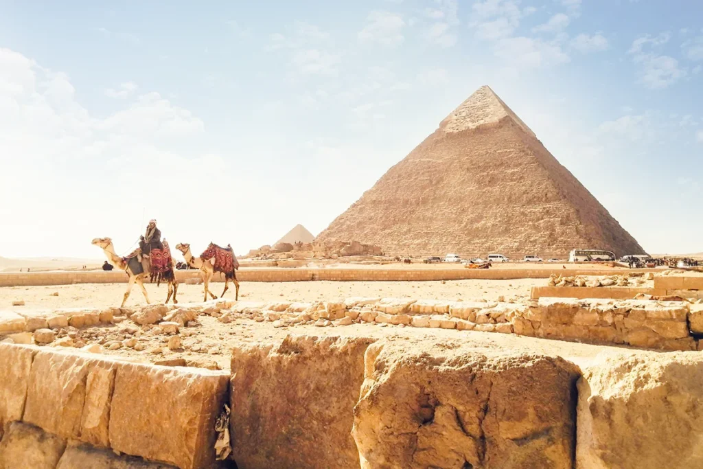 Ein Reiter und zwei Kamele vor den Pyramiden von Gizeh in Ägypten