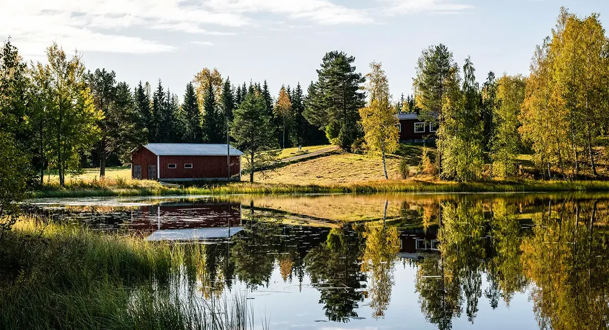 Kleine Holz-Hütten an einem See in Finnland, inmitten eines Waldes