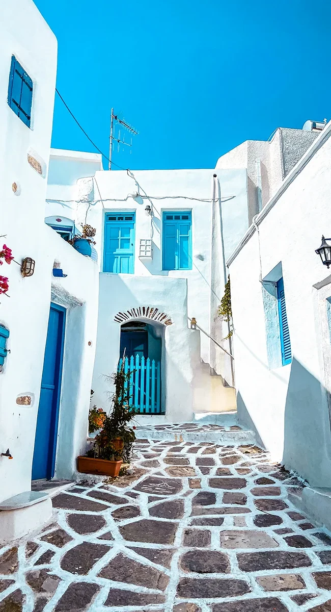 Eine Gasse auf der Insel Santorini in Griechenland mit weißen Gebäuden und blauen Türen und Fensterläden