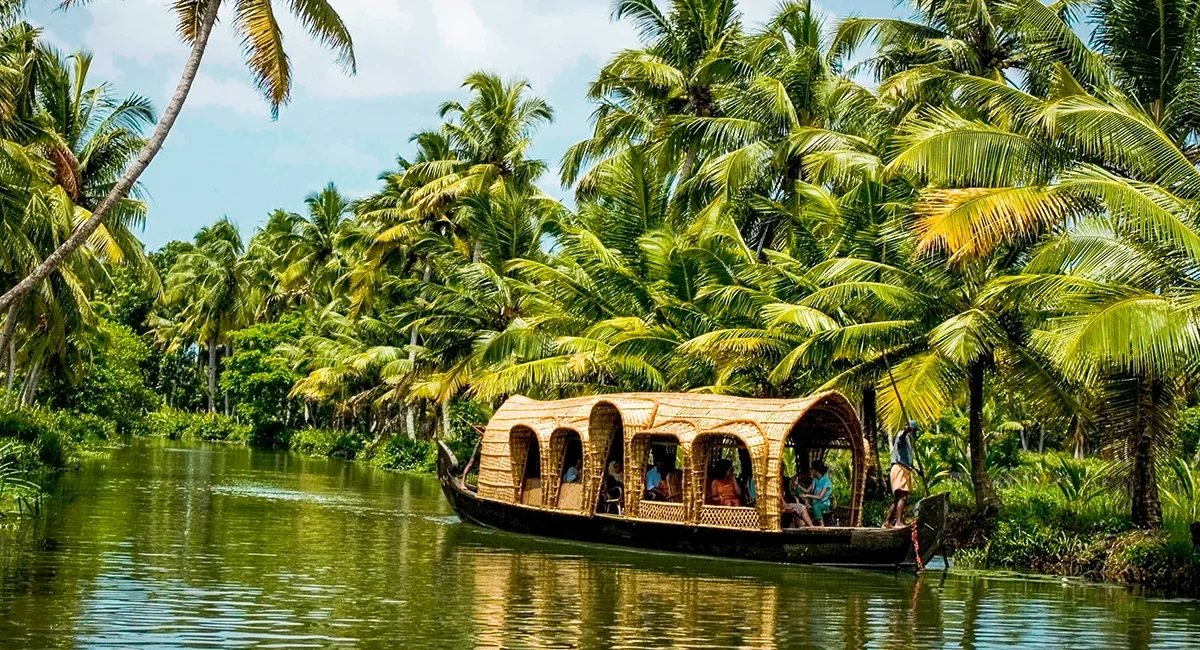 Ein traditionelles Hausboot, das durch die malerischen, palmengesäumten Kanäle der Backwaters von Kerala in Südindien gleitet.