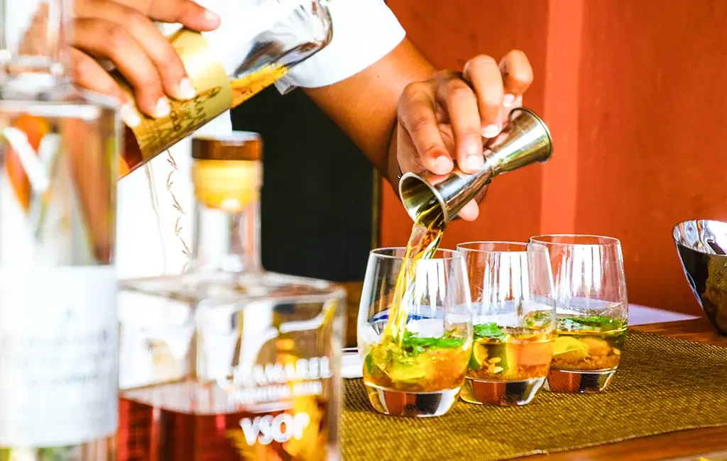 Ein Barkeeper beim Zubereiten von drei Gläsern Cuba Libre mit Rum in Kuba.