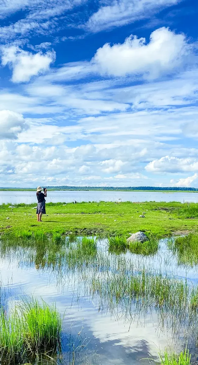An einem großen See in Lettland steht eine Person, die etwas fotografiert.