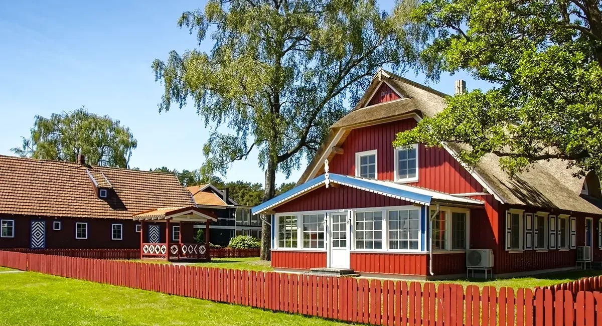 Traditionelle Fischerhäuser in Litauen mit charakteristischen braun-roten Holz und weißen und blauen Zierelementen.
