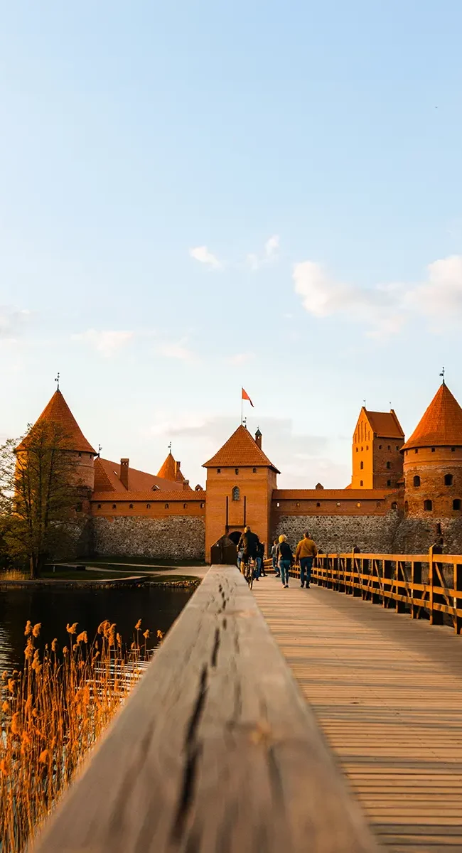 Eine lange Holzbrücke, die zur Wasserburg Trakai in Litauen führt.