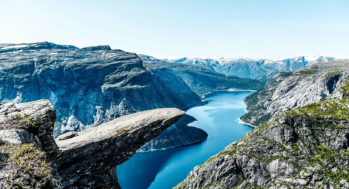 Die Trolltunga, eine spektakuläre Felsformation, die wie eine massive Zunge horizontal aus dem Berg herausragt und Hunderte von Metern über einem tiefblauen See in Norwegen schwebt.