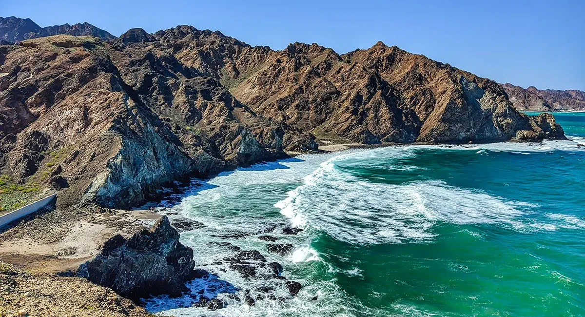 Eine felsige Küstenlandschaft im Oman mit Klippen und Felsformationen im Wasser.