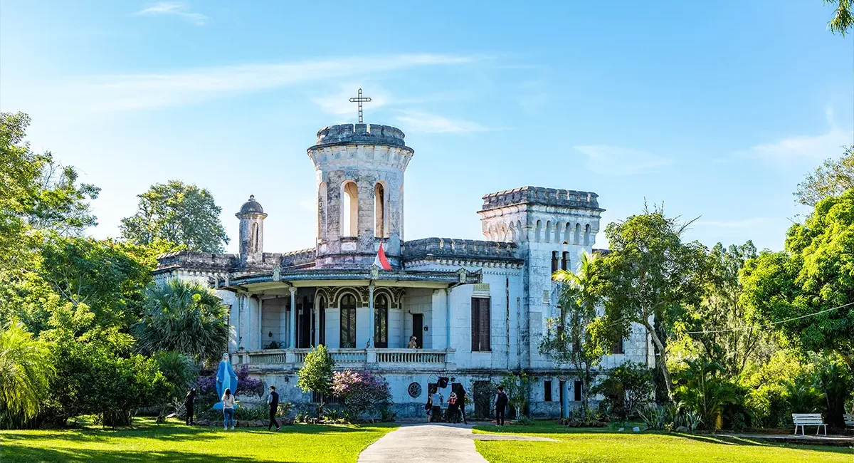 Das Castillo Carlota Palmerola, ein altes, schlossähnliches Gebäude, umgeben von üppiger grüner Vegetation in Paraguay.