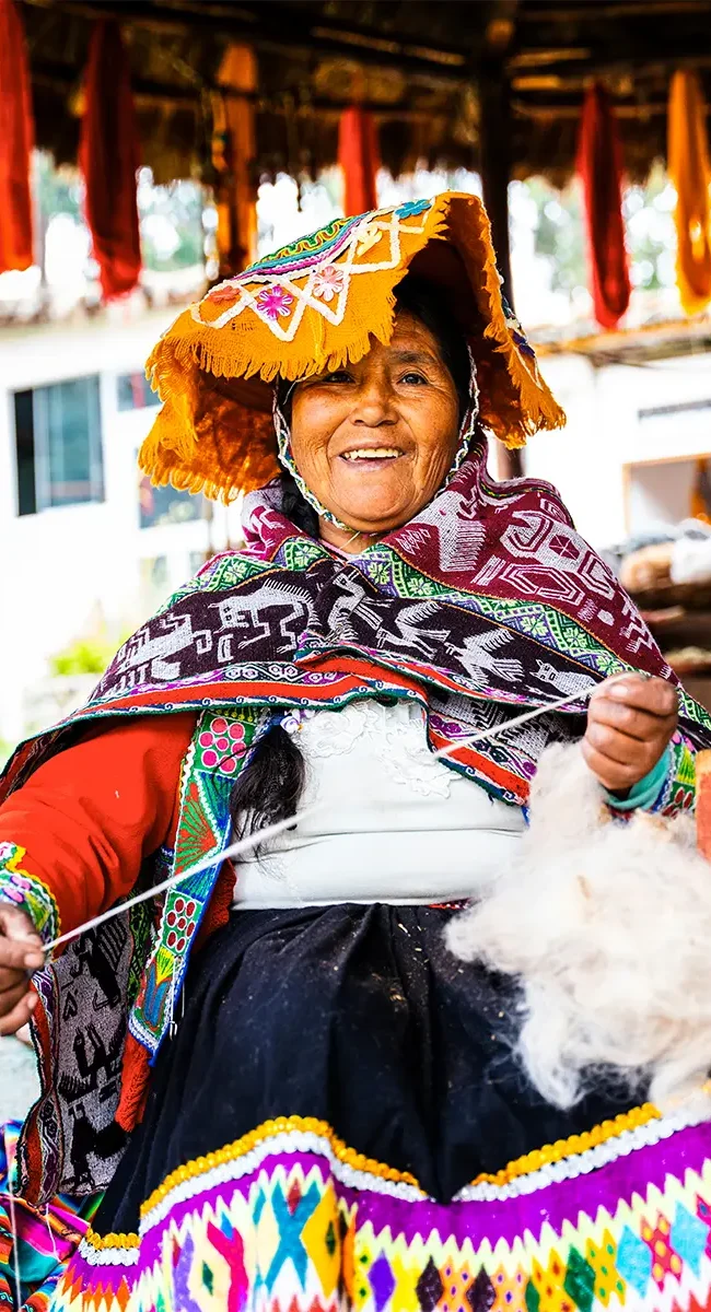 Eine einheimische Anden-Frau in traditioneller Kleidung, die in Peru von Hand Wolle spinnt.