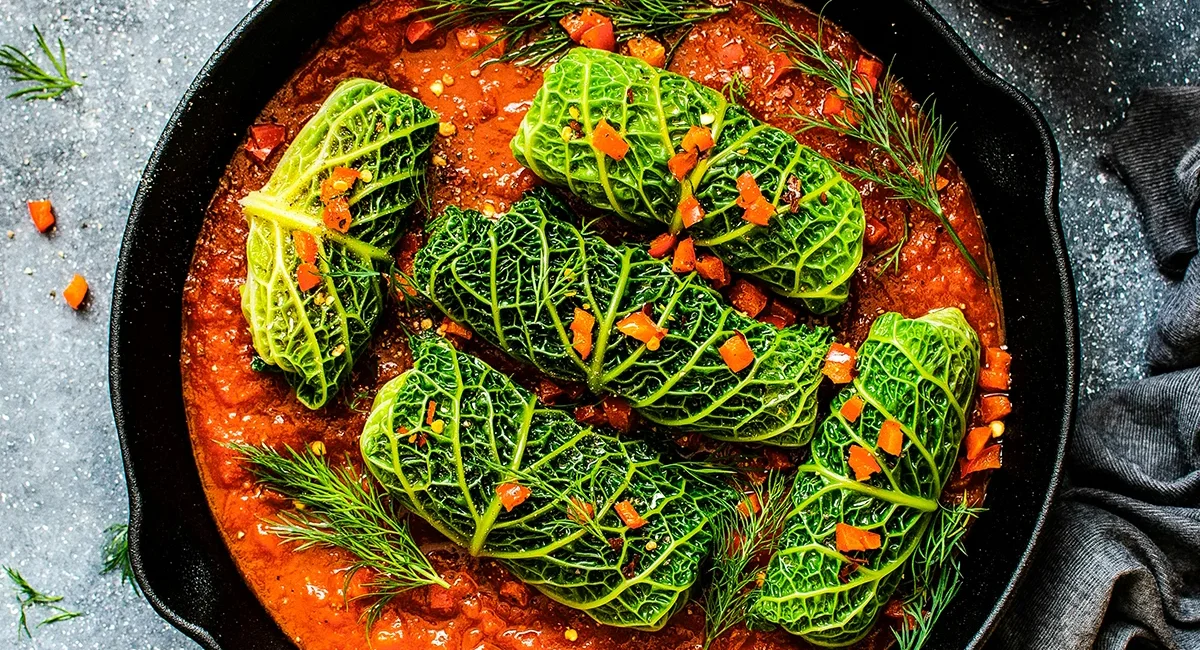 Traditionelle rumänische Kohlrouladen liegen in einer Pfanne mit roter Soße.