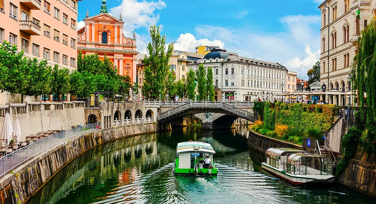 Die Drei Brücken über den Fluss Ljubljanica in der Hauptstadt Sloweniens, Ljubljana, umgeben von historischen Gebäuden und belebten Uferpromenaden.