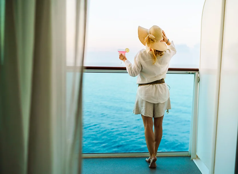 Kreuzfahrt Gruppenreise Frau steht am Fenster und genießt die Aussicht aufs offene Meer