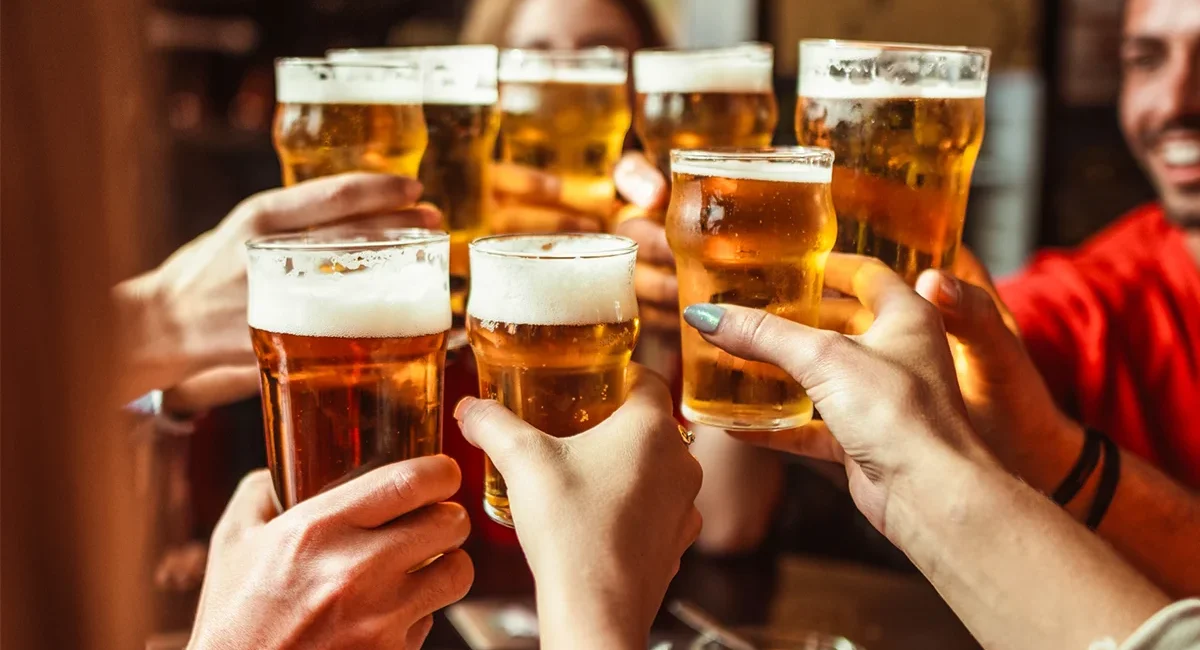 Eine Freundesgruppe stößt im Restaurant mit belgischem Bier an.