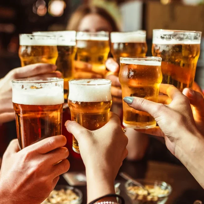 Eine Freundesgruppe stößt im Restaurant mit belgischem Bier an.