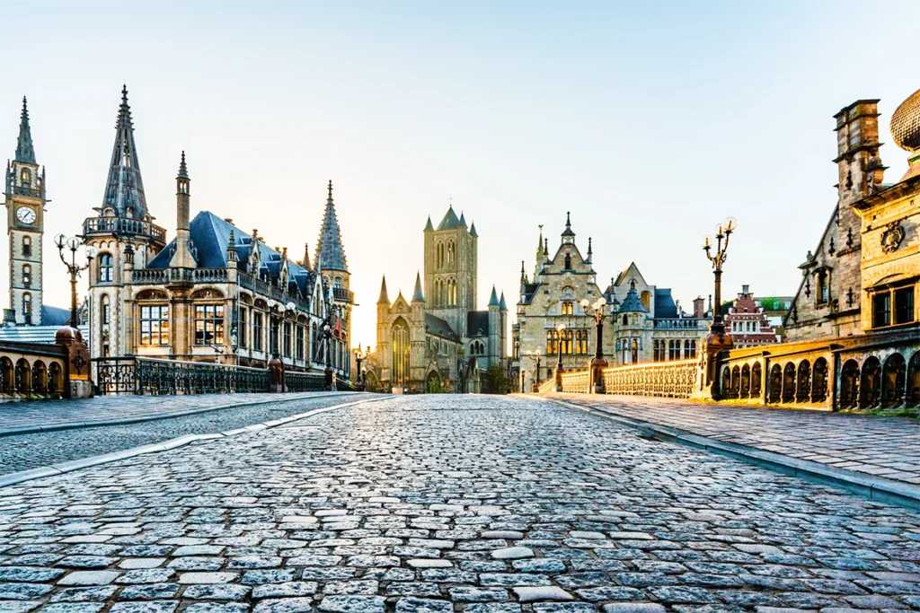 Die gepflasterte St.-Michaels-Brücke in der historischer Altstadt von Gent in Belgien, mit der markanten St.-Nikolaus-Kirche im Hintergrund.