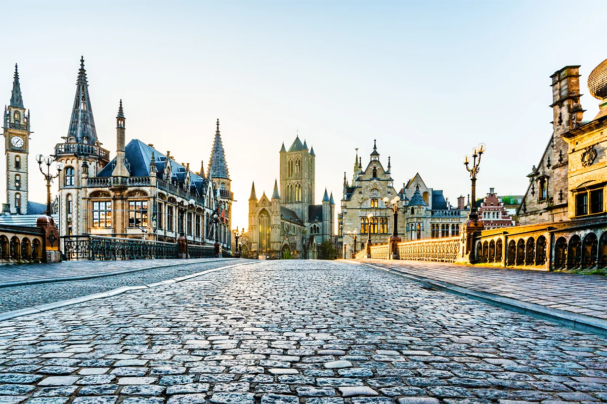 Die gepflasterte St.-Michaels-Brücke in der historischer Altstadt von Gent in Belgien, mit der markanten St.-Nikolaus-Kirche im Hintergrund.