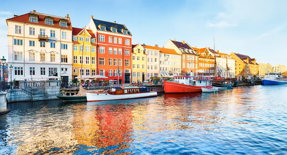 Der neue Hafen in Kopenhagen, Dänemark, bekannt für seine ikonischen, farbenfrohen Giebelhäuser und historischen Holzschiffe.