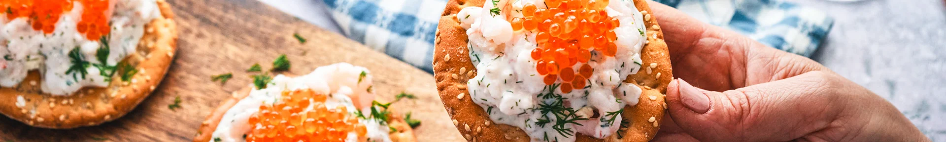 Ein Toast Skagen, eine klassische skandinavische Vorspeise aus Garnelensalat mit frischem Dill und rotem Kaviar, die auf knusprigem Crackern serviert wird.