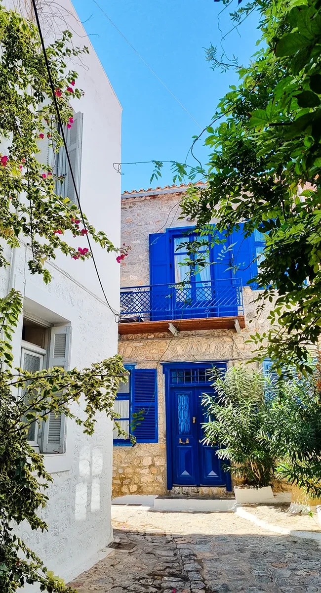 Eine malerische Gasse auf der griechischen Insel Hydra mit blauen Fensterläden.