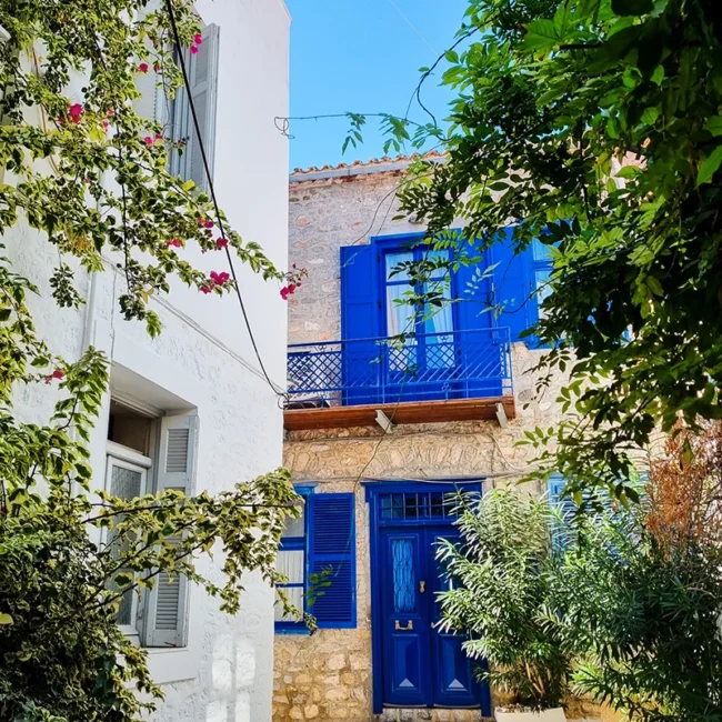 Eine malerische Gasse auf der griechischen Insel Hydra mit blauen Fensterläden.