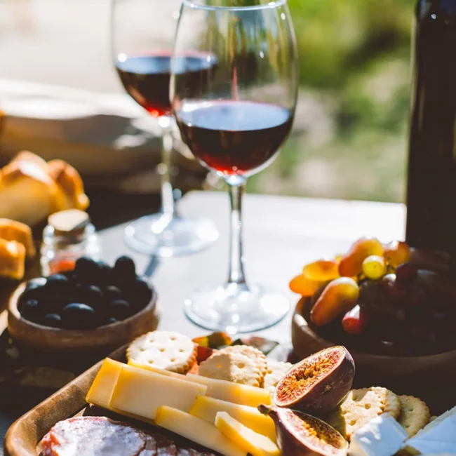Zwei Gläser Wein auf einem Tisch mit Wurst, Käse und Früchten auf Korsika.