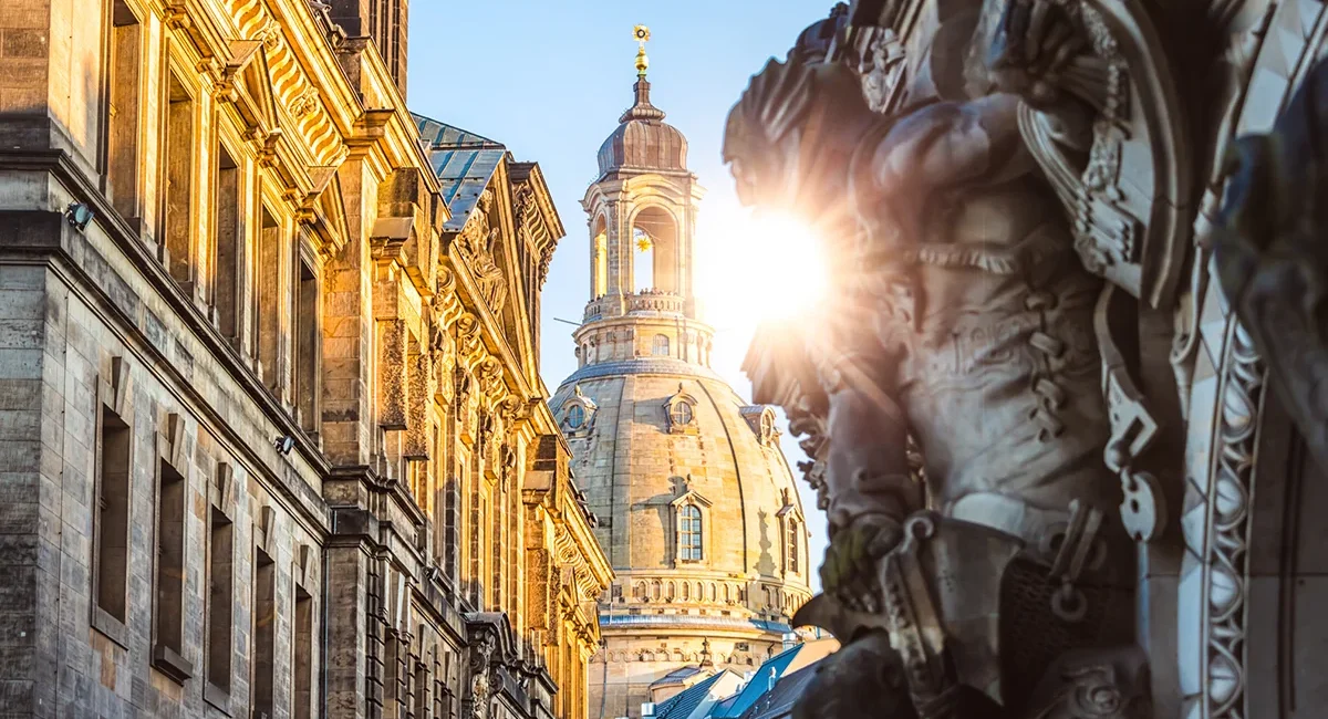 Die historische Münzgasse in Dresden mit Blick auf die markante Kuppel der Dresdner Frauenkirche, die im warmen Licht der tiefstehenden Sonne erstrahlt.