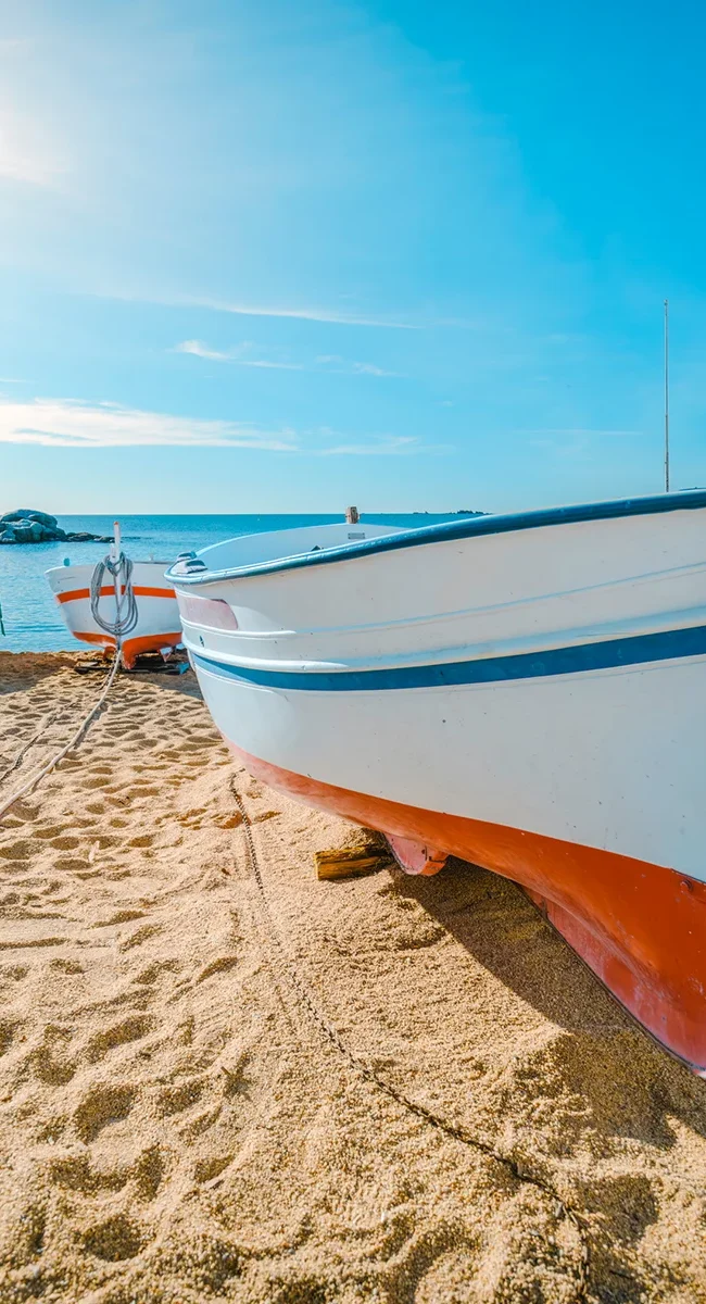 Mehrere Fischerboote liegen am Strand der Costa Brava in Spanien nahe dem Meer.
