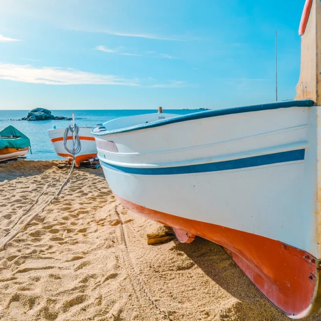 Mehrere Fischerboote liegen am Strand der Costa Brava in Spanien nahe dem Meer.