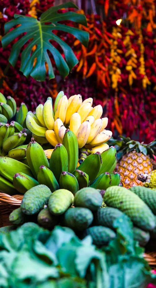 Ein Marktstand in Funchal auf Madeira mit vielen bunten Früchten. Verschiedene tropische Früchte liegen auf dem Tisch ausgestellt.