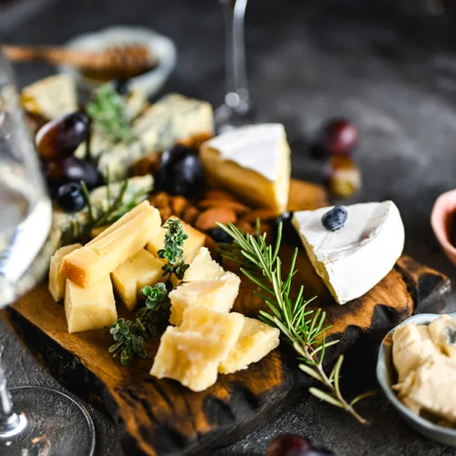 Käsebrett mit Wein, Aufstrichen und getrockneten Tomaten auf einem Tisch angerichtet