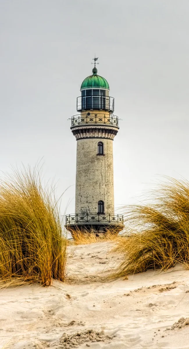 Leuchtturm in Warnemünde hinter Sanddünen an der Ostseeküste