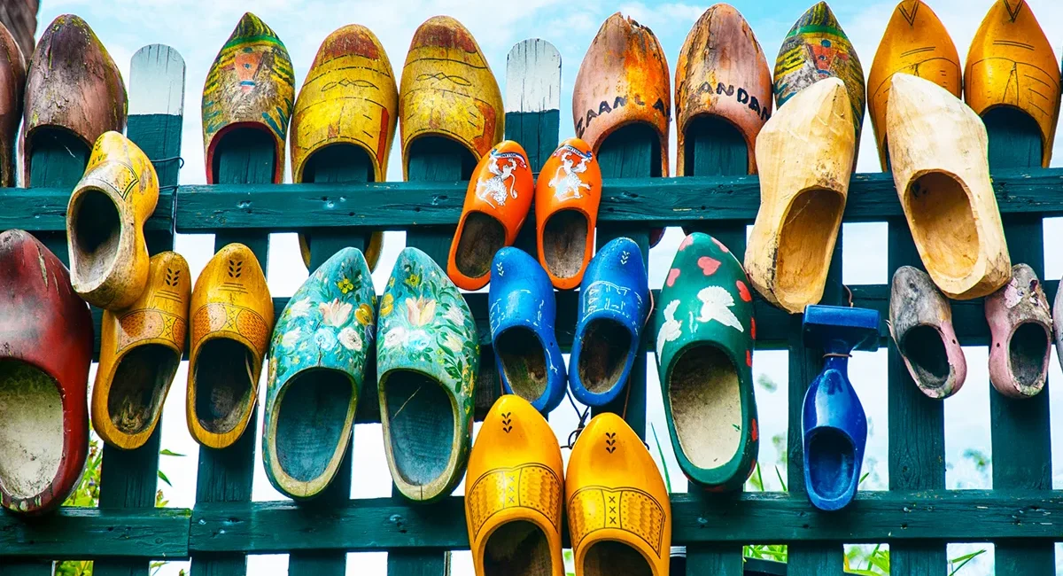 Viele bunt bemalte Holzschuhe hängen dekorativ an einem Zaun. Die traditionellen niederländischen Holzschuhe sind in verschiedenen Farben und Mustern gestaltet.