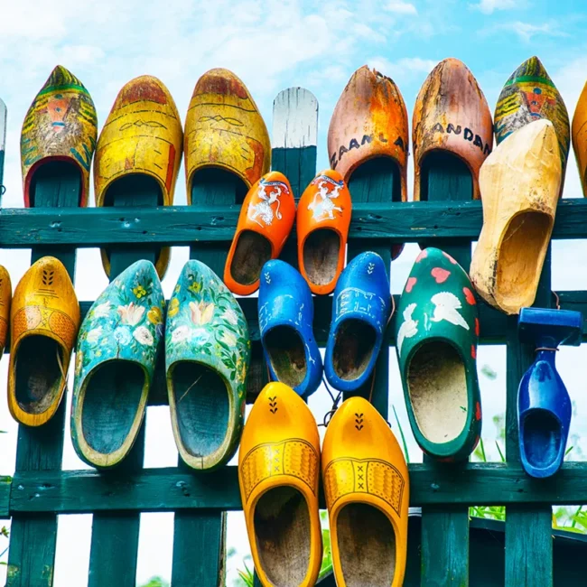 Viele bunt bemalte Holzschuhe hängen dekorativ an einem Zaun. Die traditionellen niederländischen Holzschuhe sind in verschiedenen Farben und Mustern gestaltet.