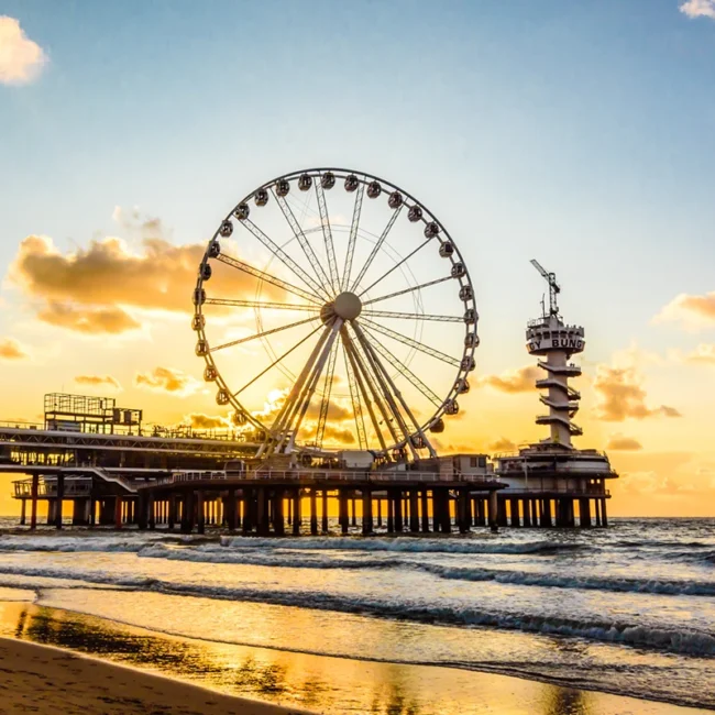 Der Pier von Scheveningen ragt ins Meer hinaus. Am Ende des Piers steht ein großes Riesenrad über der Nordsee.