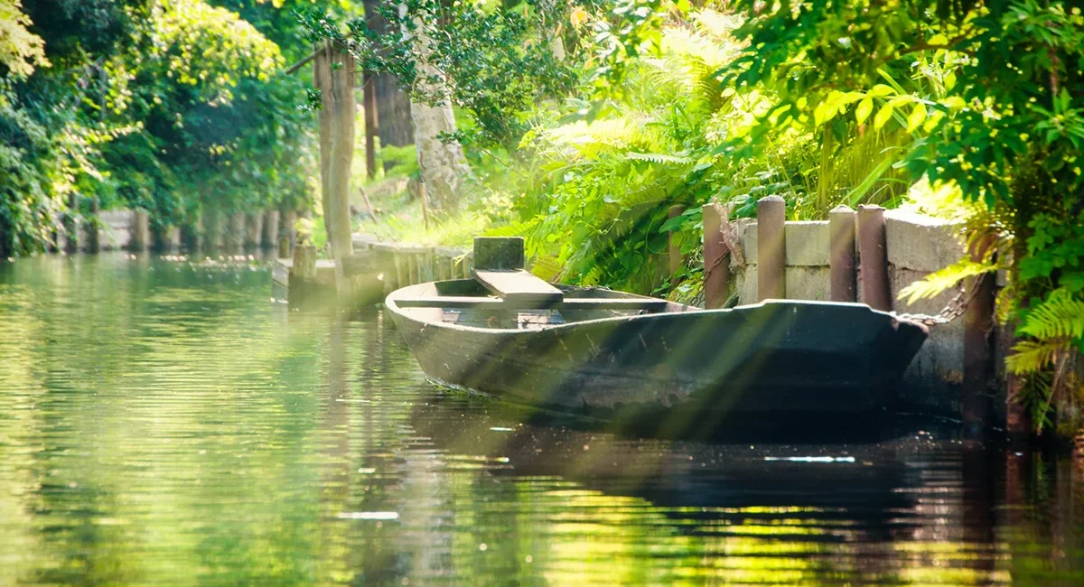Spreewaldkahn auf einem Kanal, Sonnenlicht fällt durch die Bäume auf das Wasser