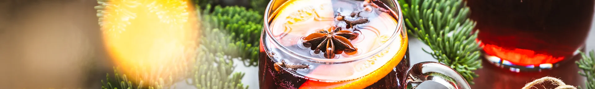 Glühwein mit Tannenzweigen und Anis als winterliche Gewürze im Becher
