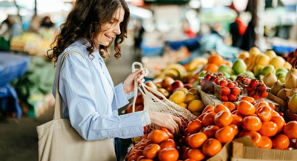 Frau kauft frisches Obst und Gemüse an einem Stand auf dem Wochenmarkt