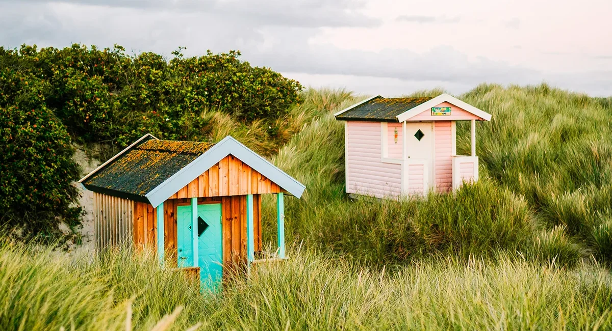 Zwei bunte Strandhütten stehen nebeneinander am Strand von Skanör in Schweden.