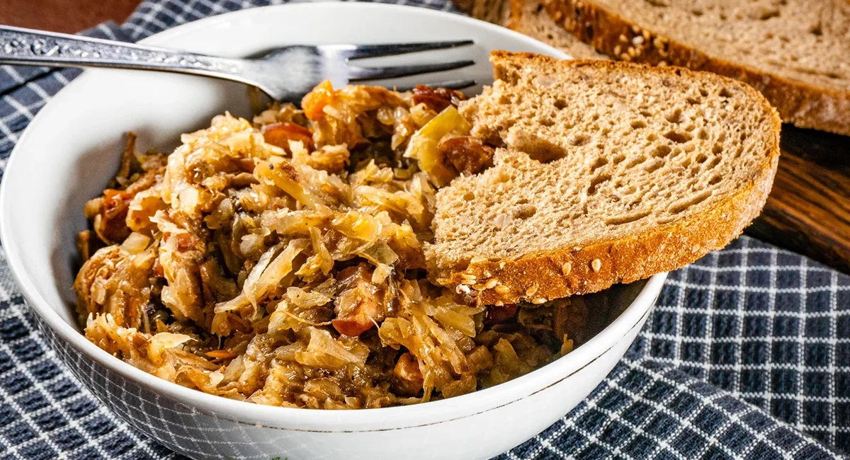 Eine Portion Bigos, ein traditioneller polnischer Eintopf aus Sauerkraut und Fleisch, wird zusammen mit Brot serviert.