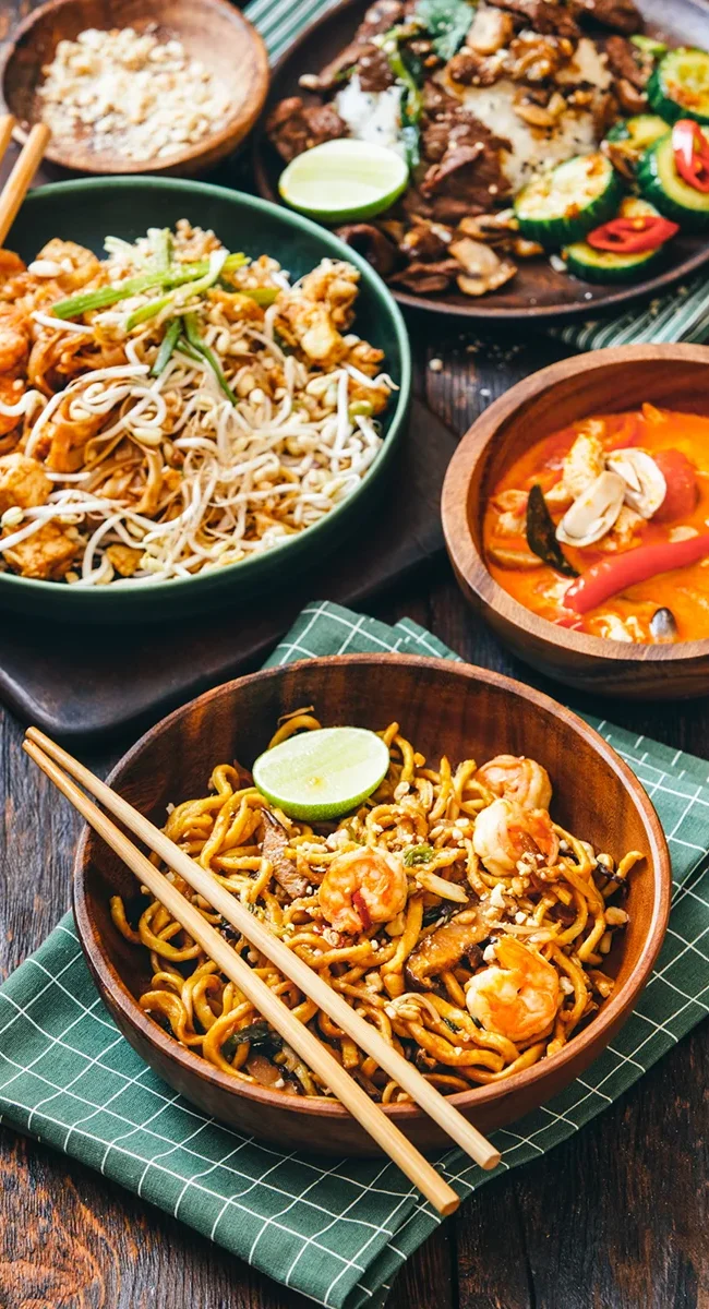Ein thailändisches Gericht mit Reisnudeln und Curry, angerichtet in einer Schale mit verschiedenen Zutaten.
