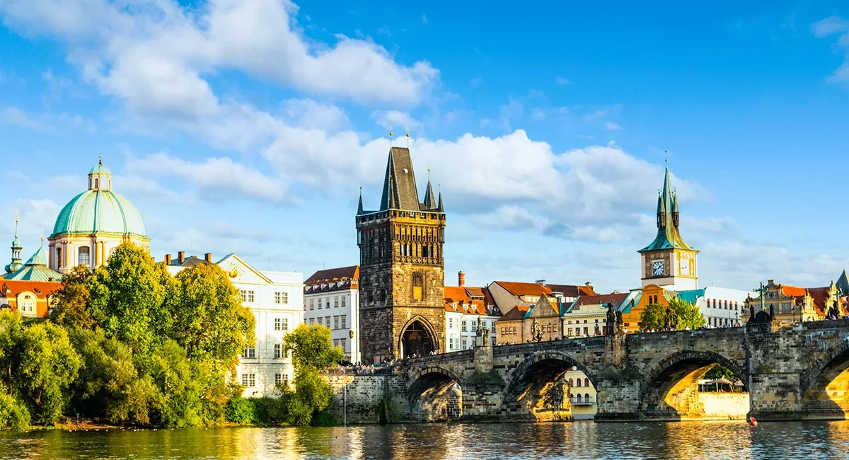 Blick von der Moldau auf die Karlsbrücke in Prag mit ihren steinernen Bögen über dem Wasser.